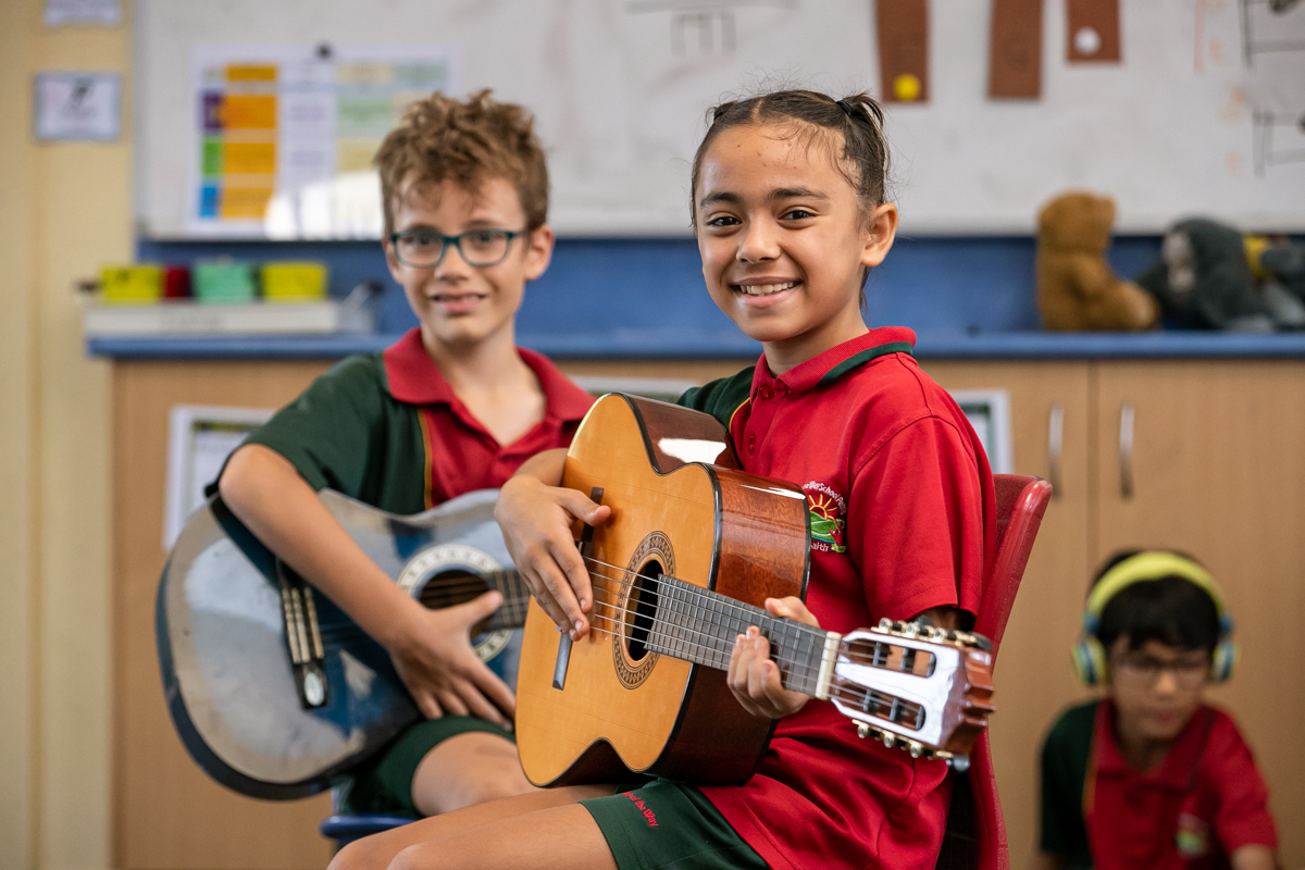 two students playing guitars